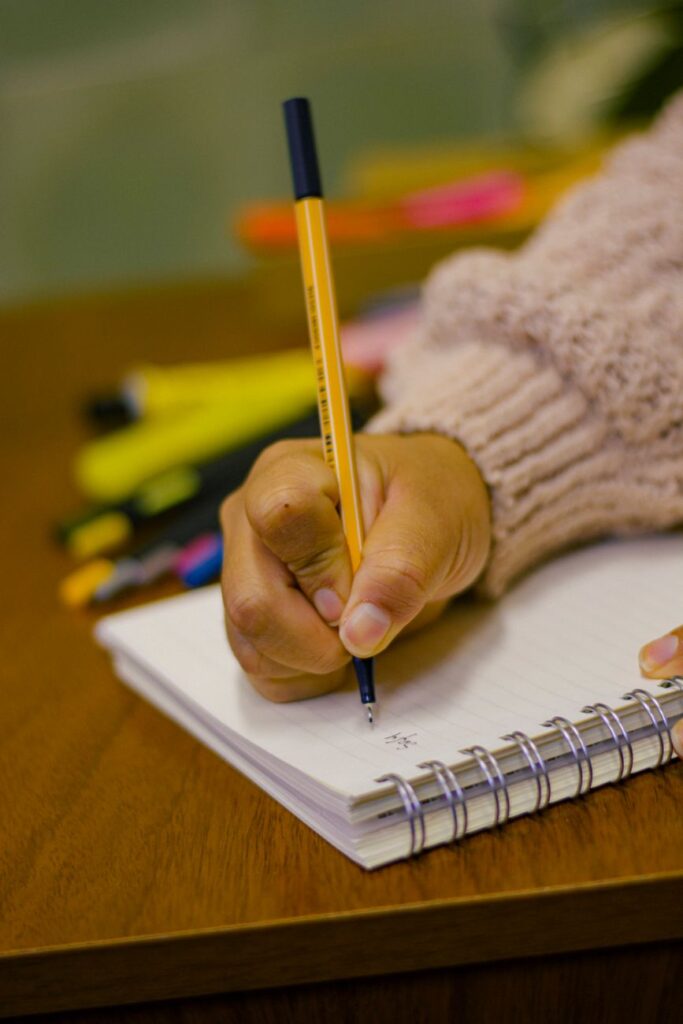 close up of hand writing in notebook with pen